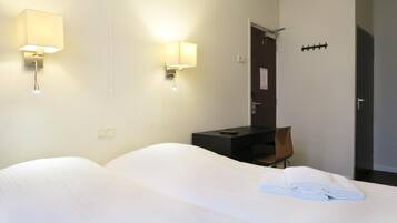 Ein Hotelzimmer mit zwei Betten, einem Schreibtisch und zwei Wandleuchten.