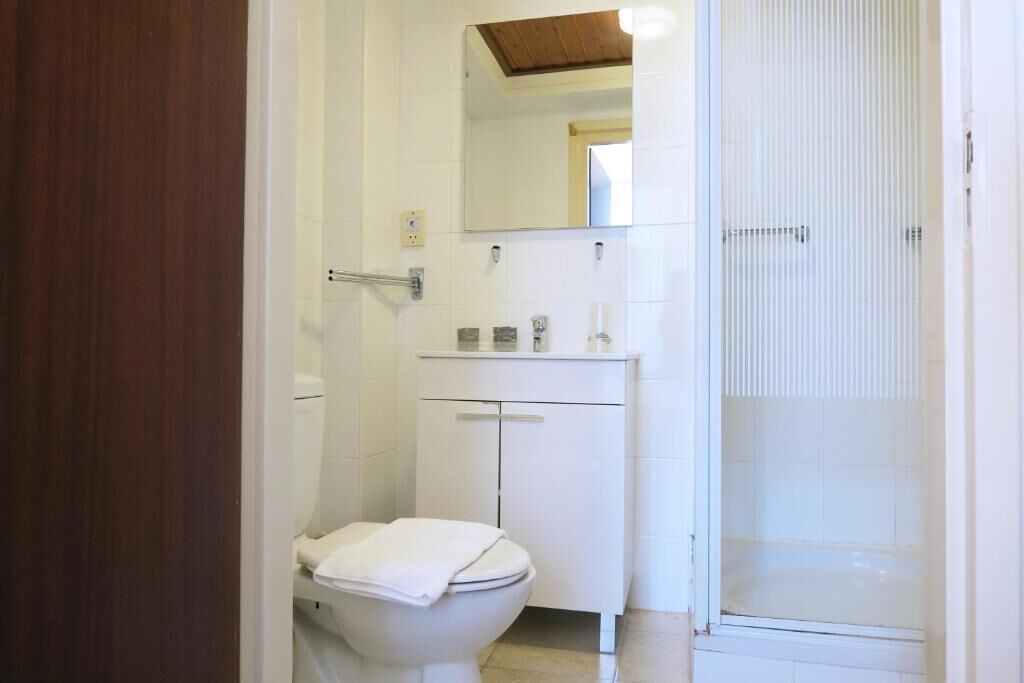 A bathroom with a toilet, a sink, and a shower area.