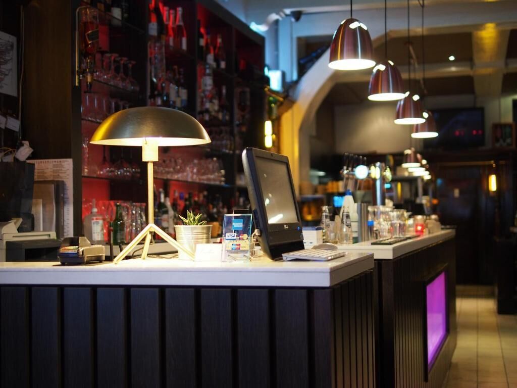 A bar counter with a computer, a cash register, and a payment terminal.