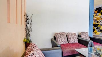 A hotel lobby with a sofa set, a glass table, and a wall-mounted plant.