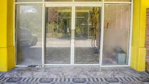 A building entrance with a glass door and a tiled floor. - Hotel O Senja Syariah (Gresik)