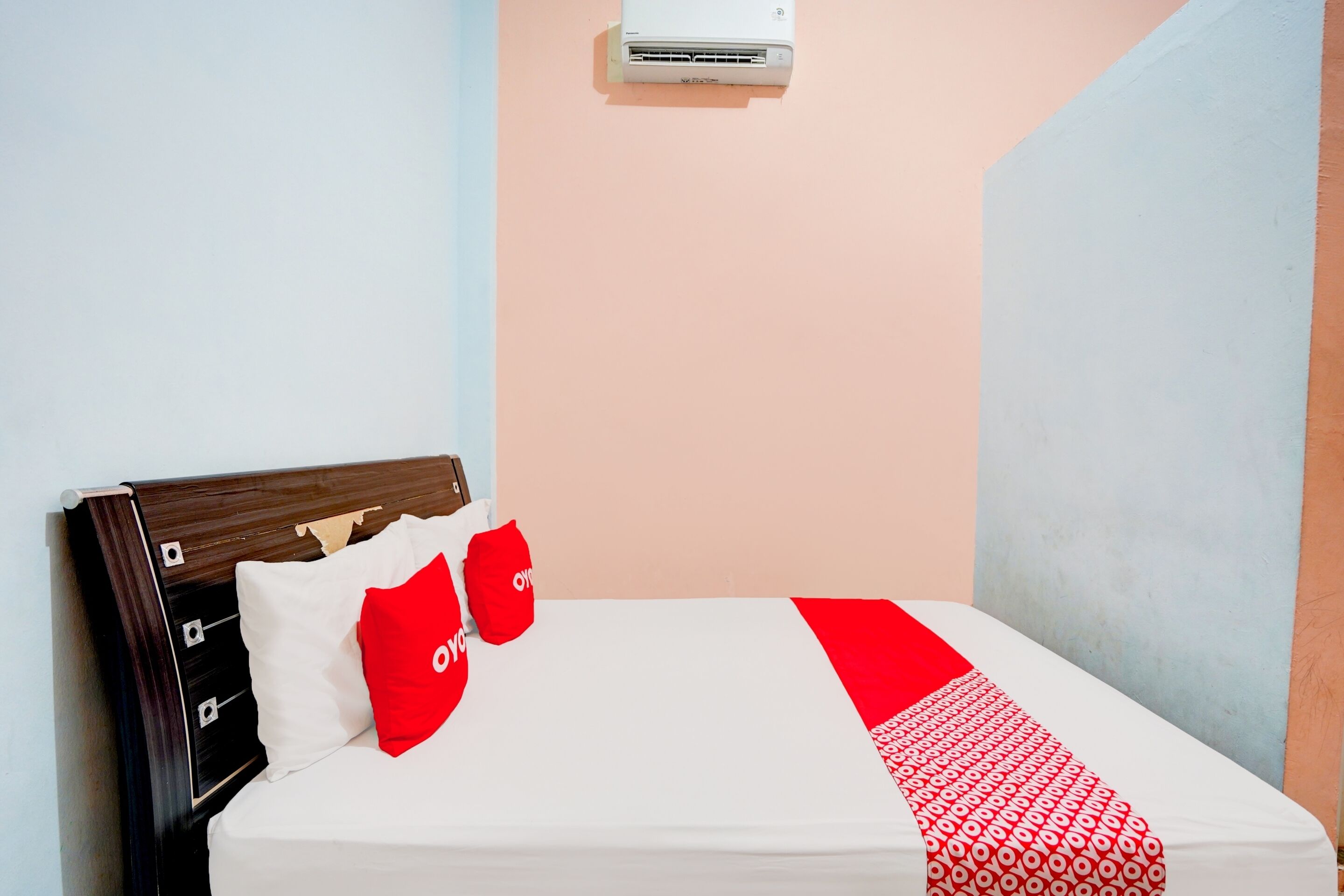 Una cama con un colchón blanco, almohadas rojas y una colcha roja y blanca.