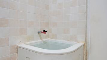 Une salle de bain avec une baignoire, des murs carrelés et des éléments de plomberie apparents.