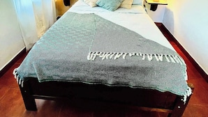 Ein Bett mit gemustertem Überwurf, zwei Nachttischlampen und einem an der Wand hängenden Bild.