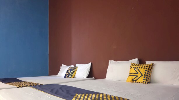A hotel room with two beds, each with white bedding and decorative pillows. - OYO Life  92842 Homestay Balearjosari (Malang)