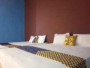 Une chambre d’hôtel avec deux lits, chacun agrémenté de draps blancs et d’oreillers décoratifs.