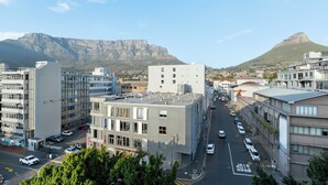 A cityscape with modern buildings, a clear sky, and a prominent mountain in the background. - Luxury On Loop with Table Mountain Views
 (Cape Town)
