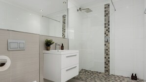 A modern bathroom with a shower, a toilet, and a vanity with drawers. - Luxury On Loop with Table Mountain Views
 (Cape Town)