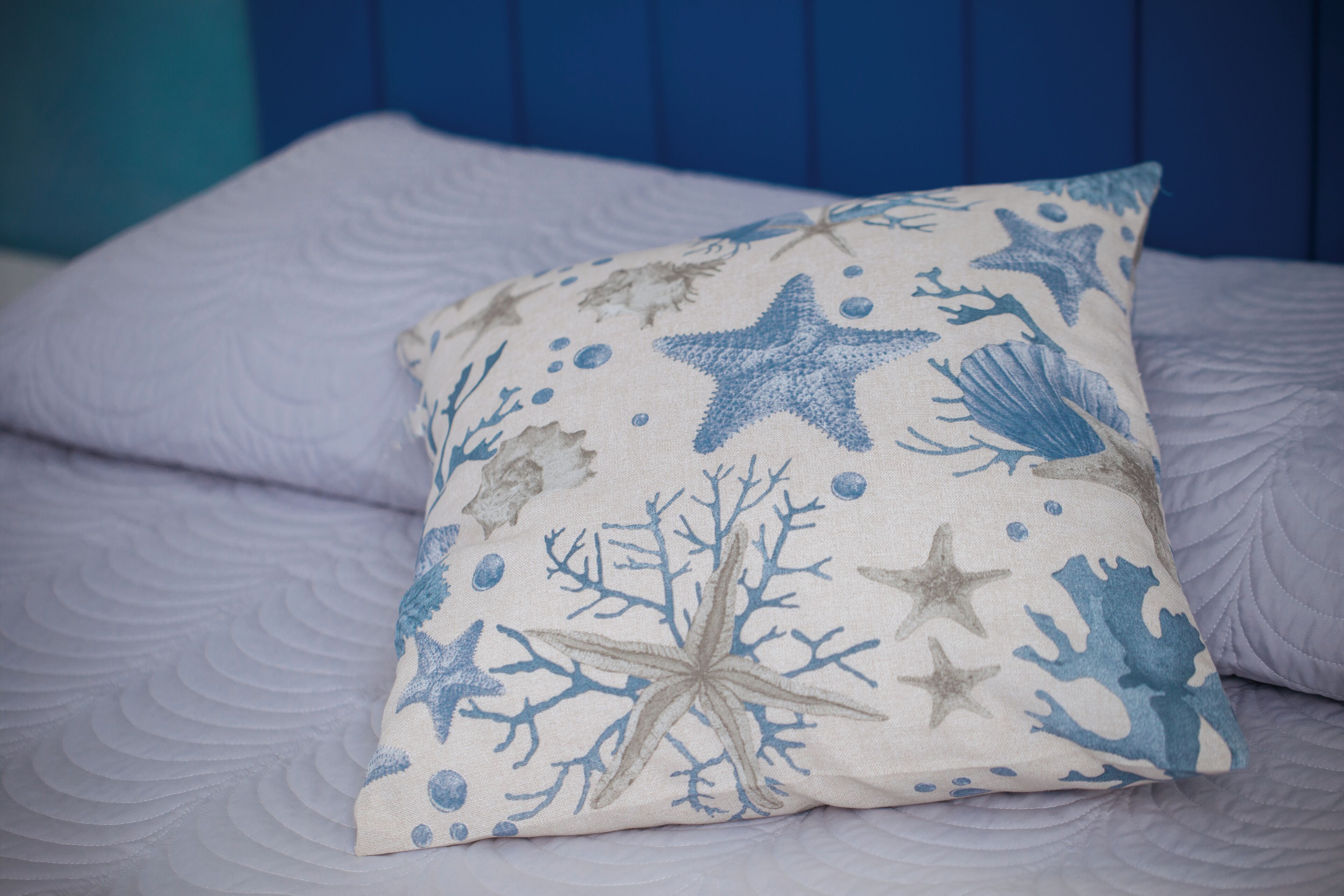 A bed with a pillow featuring a sea-themed design.