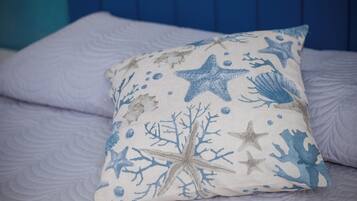 A bed with a pillow featuring a sea-themed design.
