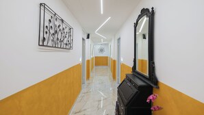 Un couloir doté d’un sol en marbre, d’une commode noire avec un miroir et d’une œuvre d’art encadrée accrochée au mur.