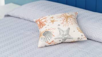 Un letto con una coperta a motivi e un cuscino decorativo a tema marino.