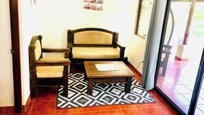 A room with a sofa, a chair, a small table, and a patterned rug. - Apartamentos El Labrador # 2 (Tamarindo)