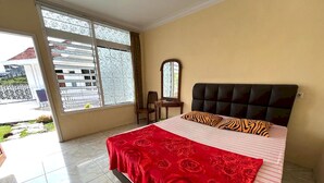 Une chambre à coucher comprenant un lit, une chaise, un bureau et une fenêtre donnant sur un immeuble et une clôture.