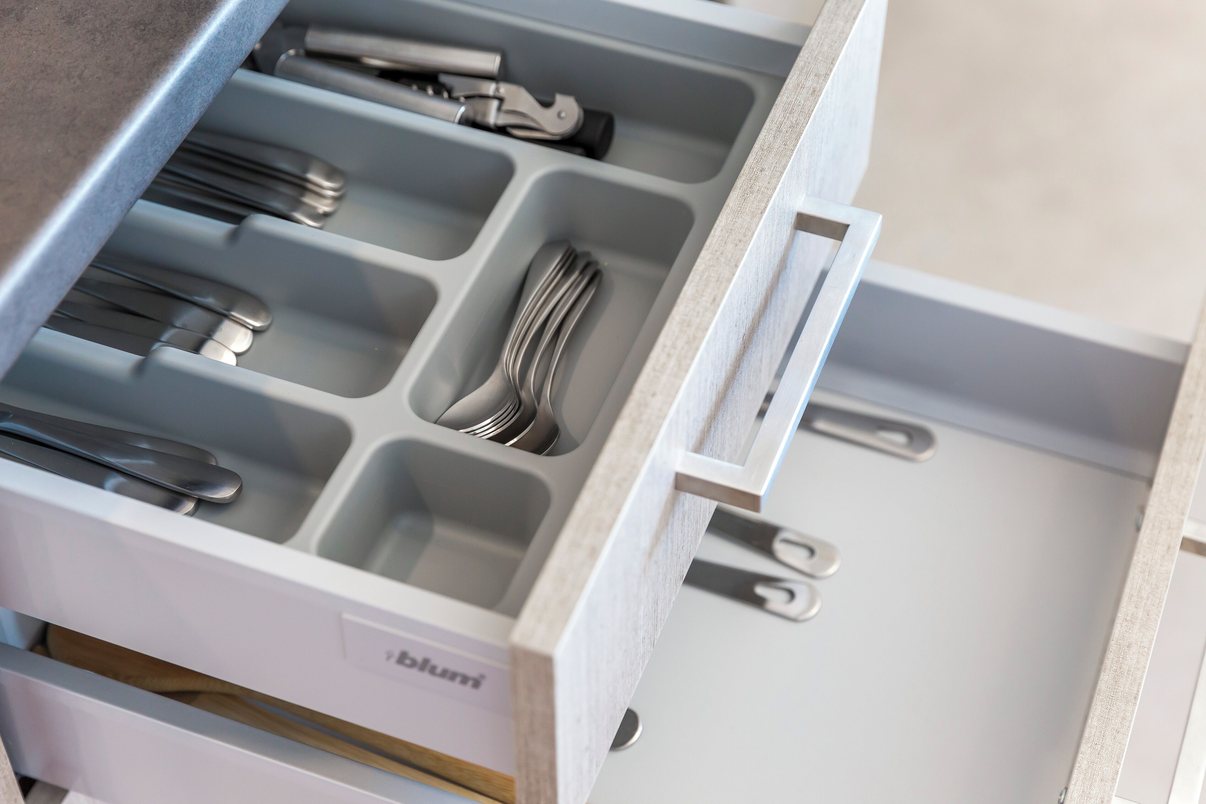 A drawer with multiple compartments, each holding different kitchen utensils.