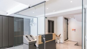 A modern reception area with a glass partition, a reception desk with a keyboard, and a potted plant. - Cubes Living Athens, Duplex Apartment 801
 (Athina)
