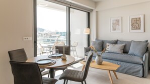 A modern living room with a grey sofa, dining table, and chairs. There are two framed artworks on the wall. - Cubes Living Athens, Duplex Apartment 801
 (Athina)
