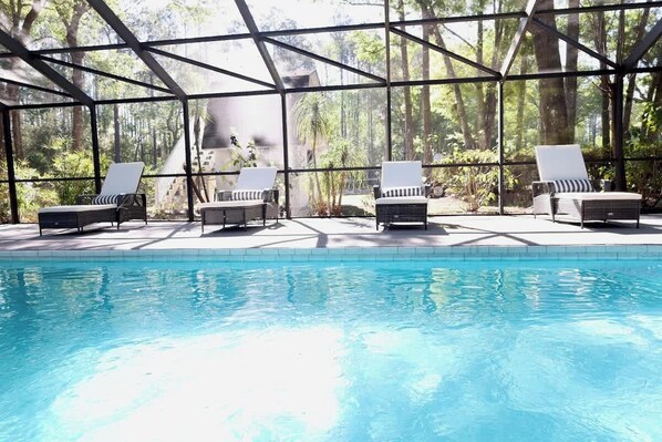 A pool area with lounge chairs and a glass-enclosed structure.