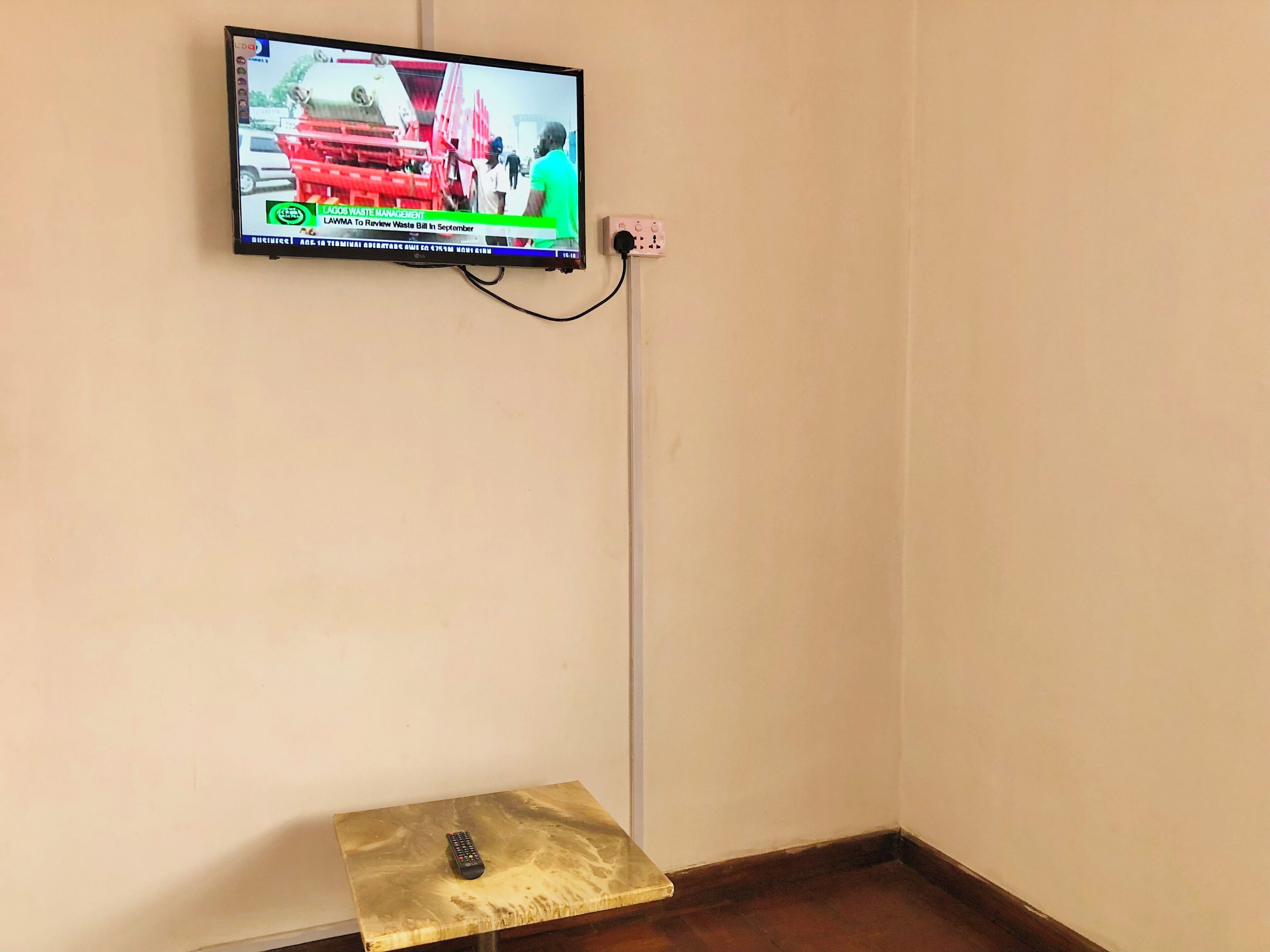 Ein an einer Wand befestigter Fernseher zeigt eine Nachrichtensendung über Abfallwirtschaft.