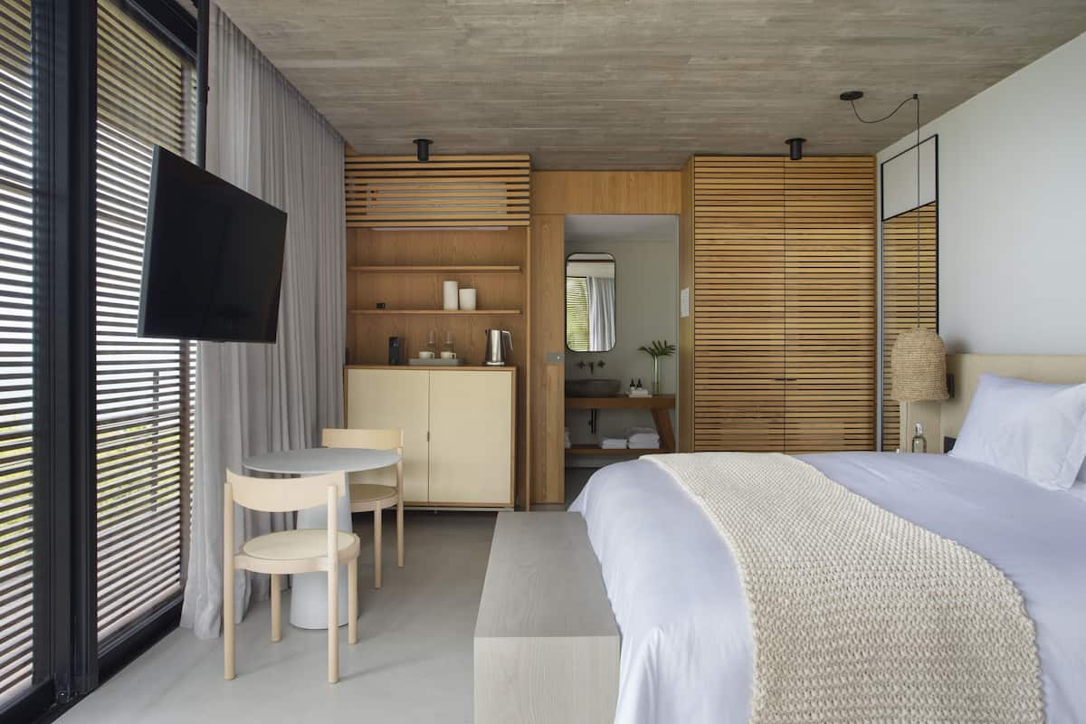 A modern bedroom with a bed, bedside table, and a desk with a chair.