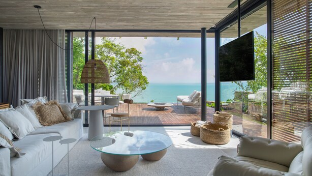 A modern living room with a glass coffee table, white sofas, and a view of the ocean. - Fuso Concept Hotel (Florianópolis)