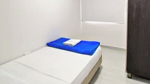 A small, single-bed room with white walls, a dark door, and a window with blinds. - Apartahotel222 Apto 401 (Pereira)