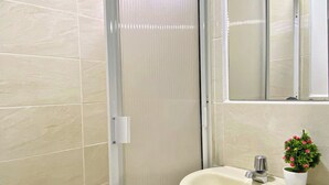 A bathroom with a shower, a sink, a mirror, and a potted plant. - Apartahotel222 Apto 401 (Pereira)