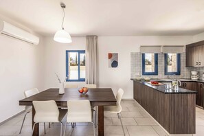 Uma cozinha moderna com uma ilha central, cadeiras brancas e uma mesa de jantar.
