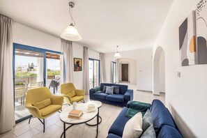 Uma sala de estar ampla com sofá, poltronas e mesa de centro.
