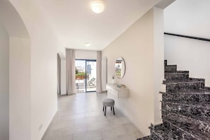 A modern interior with a staircase, a white desk, and a view to the outside. - Coral Olympus Apollo (Peyia)