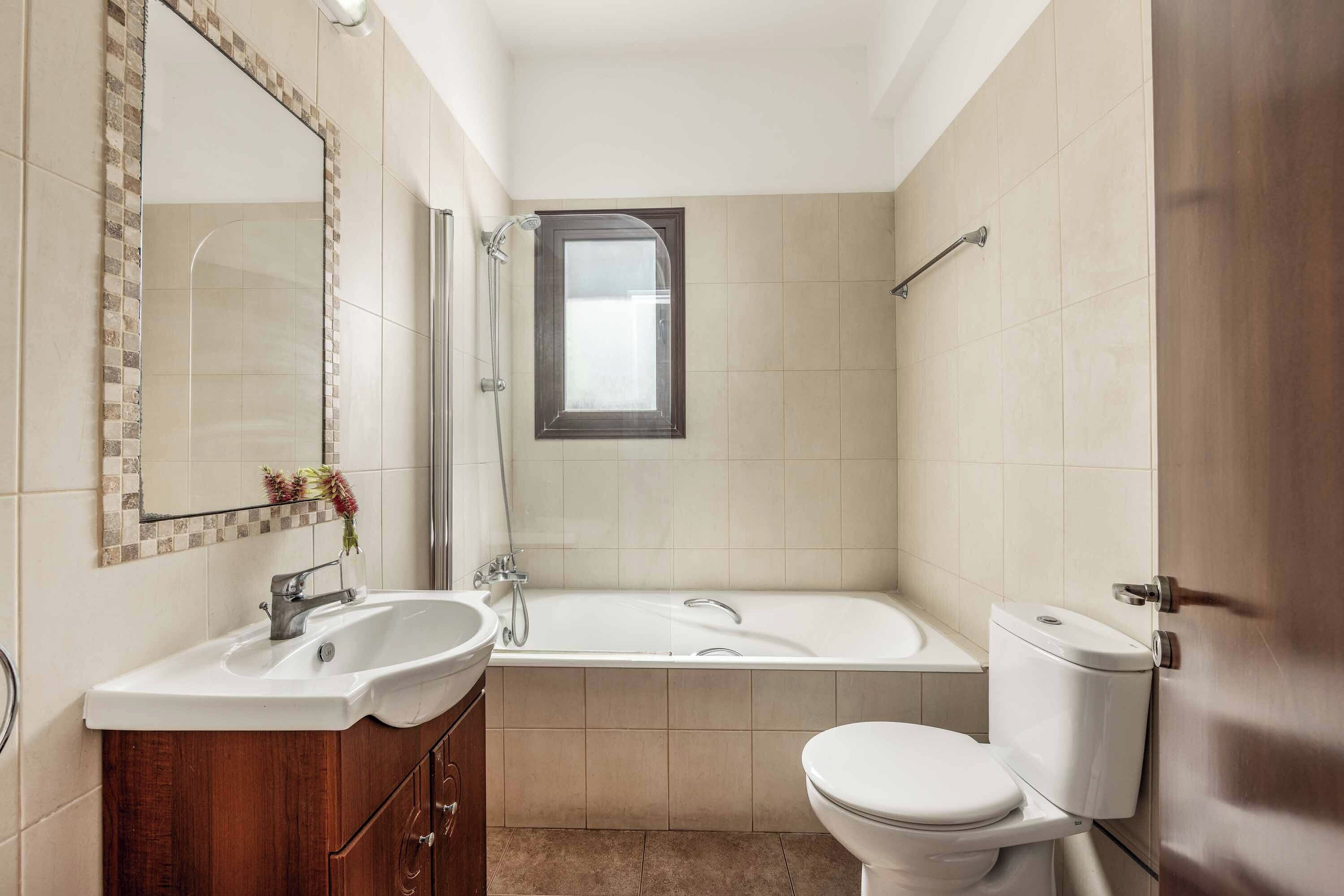 Une salle de bain comprenant un lavabo, un miroir, un meuble-lavabo, une baignoire, une douche et des toilettes.