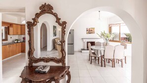 A spacious dining area with a white table and chairs, a large ornate mirror, and a view through an archway to the kitchen. - Villa Kyveli 2 - Three Bedroom Villa, Sleeps 6 (Peyia)