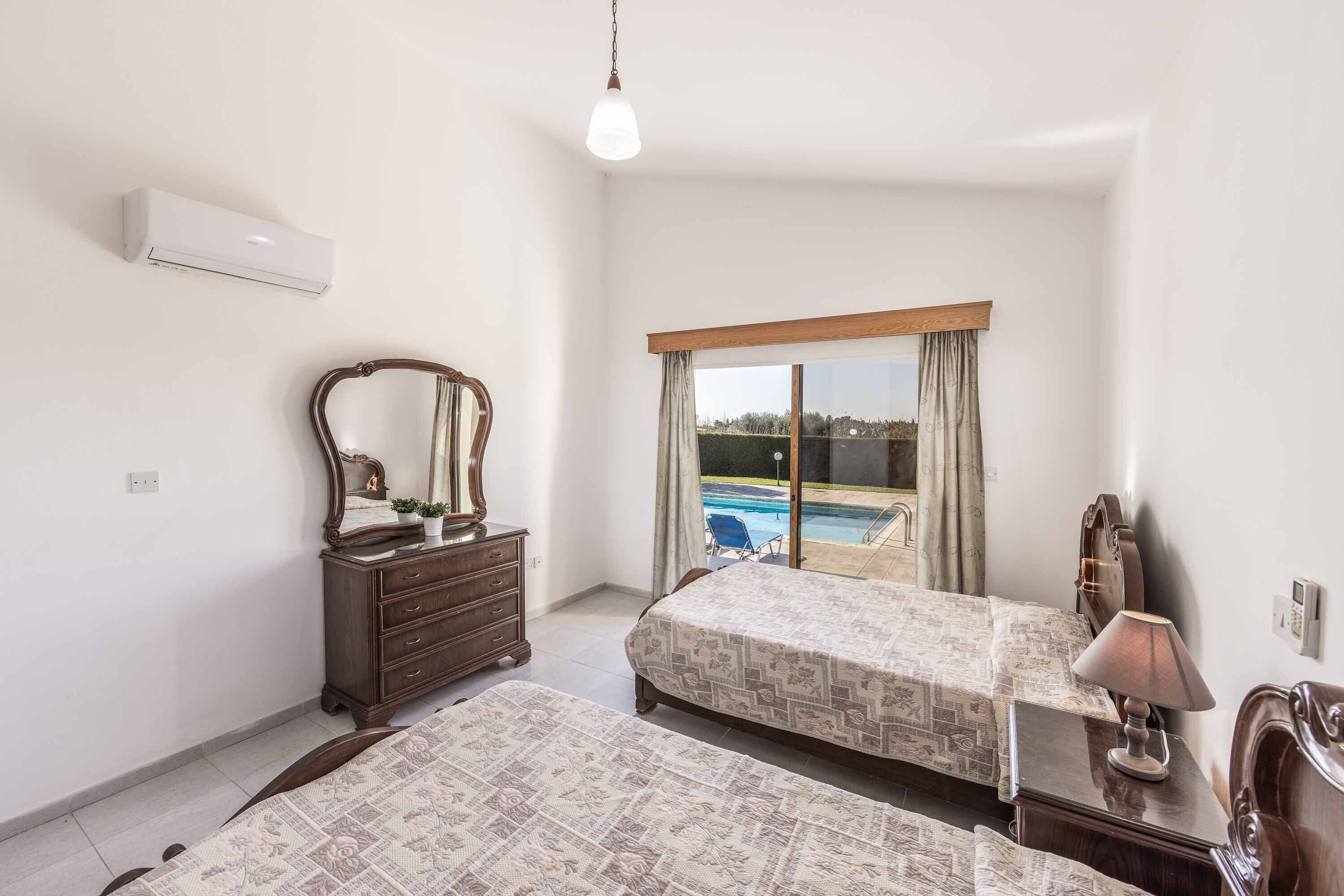 A bedroom with two beds, a dresser, a mirror, and a window with a view of a swimming pool.