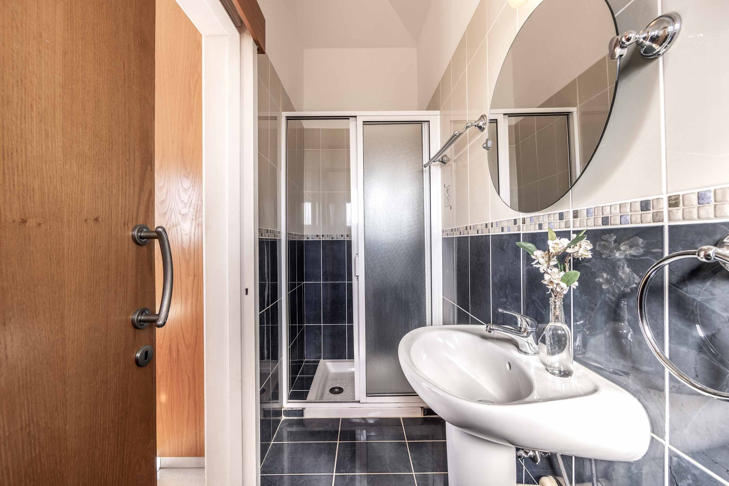 A modern bathroom with a shower, a sink, and a mirror.