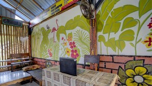 Une pièce comprenant une table, des chaises, un ordinateur portable et un mur orné de tableaux représentant des fleurs et des oiseaux.