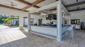 An outdoor dining area with a bar, ceiling fans, and a view of the garden. - Storey Lake-Disney Pool Townhome FREE Water Park (Kissimmee)