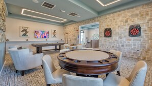 A modern conference room with a round table, comfortable seating, a stone accent wall, and dartboards. - Storey Lake-Disney Pool Townhome FREE Water Park (Kissimmee)