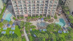 Un hôtel de grande hauteur doté de nombreux balcons, d’une cour intérieure avec des piscines et d’un jardin bien entretenu.
