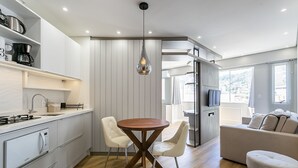 A modern kitchen with white cabinetry, a wooden dining table, and two white chairs.