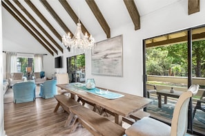Relax in this serene space with a dining table for four, a large abstract painting, and a chandelier.