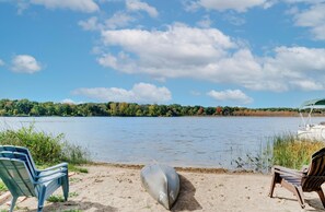 Relax on the lakeside with two lounge chairs facing the serene water and distant tree line.