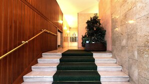 A staircase with green carpeted steps, wooden walls, and a potted plant. - Milan Hub - Sempione, Citylife, MiCo (Milano)
