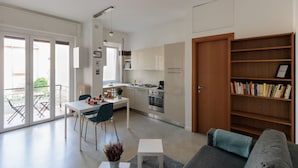 A modern apartment with a kitchen, dining area, and a living room with a sofa and bookshelf. - Milan Hub - Sempione, Citylife, MiCo (Milano)
