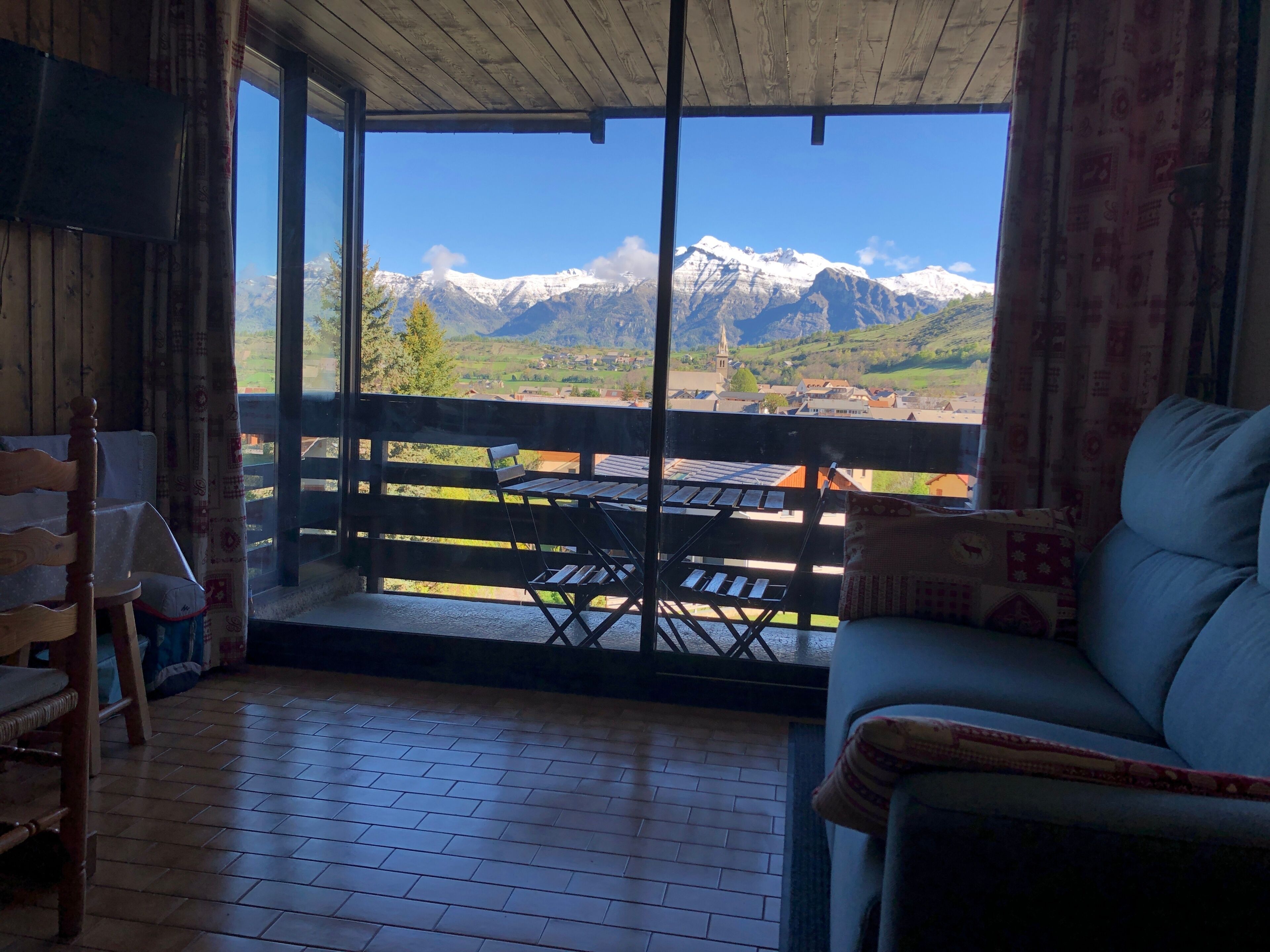 Ein Zimmer mit Holzboden, einer Couch, einem Tisch und Blick auf schneebedeckte Berge.