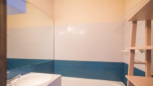 Un baño con un lavamanos blanco, una bañera y paredes con azulejos azules.