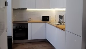 Una cocina moderna con armarios blancos, encimera de madera, microondas y estufa.