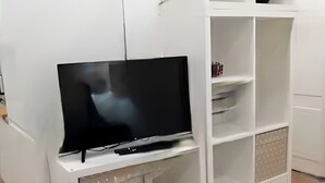 Un mueble multimedia blanco con televisor de pantalla plana, estanterías integradas y armarios.