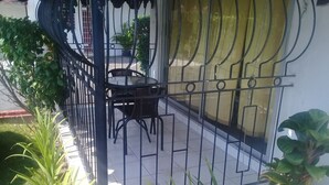 A balcony with a metal railing, a small table, and chairs. There are potted plants around the area. - Tranquille2, Jamaica vacation Kingston/St. Andrew
 (Kingston)