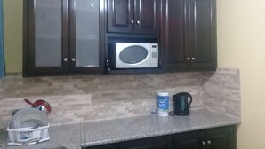 A kitchen with dark wooden cabinets, a microwave, a kettle, and a dish rack with dishes. - Tranquille2, Jamaica vacation Kingston/St. Andrew
 (Kingston)