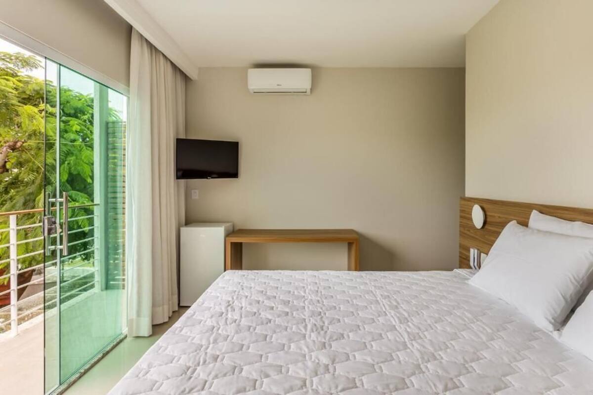 A hotel room with a large bed, a TV mounted on the wall, and a balcony with glass doors.